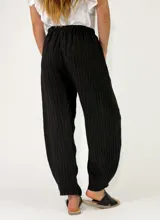 Pantalón de lino azul marino con diseño de rayas diplomáticas verticales claras, corte holgado y cintura elástica fruncida.