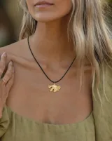 Collar con tira de cuero negra y dije colgante de hoja dorada.