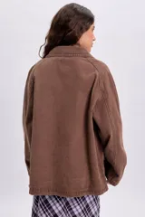 Campera de jean color marrón con efecto lavado, cuello camisero, cierre frontal con botones y bolsillos laterales.