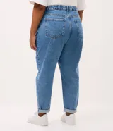 Pantalón mom jeans de tiro alto con lavado efecto mármol, corte holgado en cadera y piernas con ruedo ajustado. Cuenta con trabillas en la cintura, bolsillos funcionales y cierre frontal con botón.