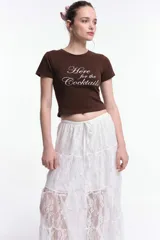 Remera blanca de algodón con corte al cuerpo, mangas cortas y cuello a la base. Presenta una estampa localizada en el frente con el texto "SUMMER GARDEN" en azul y un diseño floral en tonos rosados.
