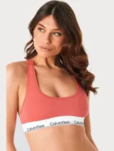 Bralette deportivo Calvin Klein de la línea Modern Cotton, sin forro ni relleno. Confeccionado en mezcla de algodón y modal, presenta un diseño de espalda cruzada y banda elástica inferior con el logo de la marca.