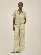 Pantalón ancho con estampado floral en tonos verde y blanco, con pinzas en el frente, bolsillos laterales y elástico en la cintura.