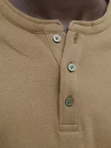Camiseta de manga larga con cuello henley y cierre frontal de tres botones. Confeccionada en algodón orgánico de textura suave, presenta un corte regular y diseño clásico.