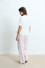 Pijama compuesto por una remera de cuello redondo en color blanco con un pequeño estampado de labios rojos en el pecho y un pantalón largo de corte holgado con estampado de rayas verticales y labios rojos sobre fondo claro.
