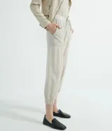 Pantalón jogger Marfinno color beige, confeccionado en suedine con cintura elástica y cordón ajustable. Presenta detalles perforados en los bolsillos laterales y en las costuras laterales, además de puños elásticos en los tobillos.