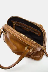 Bolso mini bandolera de cuero sintético en color tostado, con doble asa corta de mano, herrajes metálicos dorados y cierre superior con cremallera.