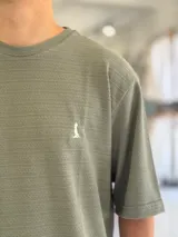 Remera oversize de tejido texturizado en color verde militar, con cuello redondo y mangas cortas. Presenta un pequeño bordado blanco en el pecho.