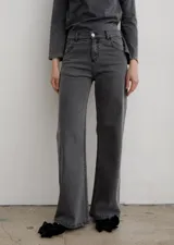 Pantalón de jean de corte recto y tiro medio, con acabado lavado en tono gris oscuro. Presenta cierre frontal con botón metálico, bolsillos laterales y traseros.