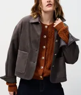 Campera de gamuza sintética color tostado con botones dorados grabados, cuello camisero, bolsillos frontales aplicados y mangas largas con puños abotonados.