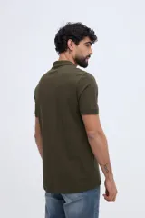 Remera polo verde militar de algodón pima, con cuello y puños acanalados, cierre frontal de tres botones y pequeño bordado de ave en el pecho.