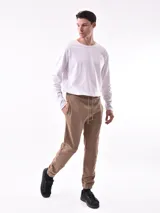 Pantalón de jogging negro, de corte ajustado con puños elásticos en los tobillos y cordón de ajuste en la cintura. Presenta paneles superpuestos en las rodillas y un pequeño texto vertical estampado en la pierna derecha.