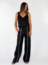 Pantalón marrón de lino de corte recto y holgado, con costuras decorativas claras a lo largo de las piernas.