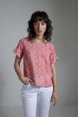 Blusa estampada fucsia y beige con cuello redondo y mangas cortas con volados.