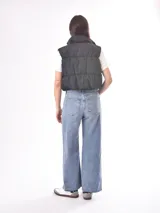 Chaleco negro con cuello alto y cierre frontal con botones a presión.