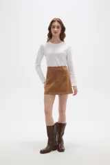 Falda mini de corte recto confeccionada en gamuza sintética color marrón, con cierre frontal de botón y presillas para cinturón.