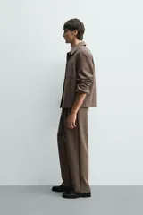 Sobrecamisa negra de corte boxy fit en tejido compacto, con cuello solapa, manga larga con puño abotonado, bolsillos frontales aplicados y cierre frontal de botonadura.