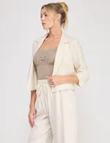 Blazer corto de lino color beige, marca Allie Rose, de estilo relajado y corte crop con frente abierto sin botones. Presenta solapa de muesca y mangas tres cuartos con detalle fruncido en los laterales.