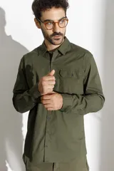 Camisa de manga larga confeccionada en algodón ripstop, con cuello clásico, cierre frontal de botones y un bolsillo en el pecho con solapa y botón.
