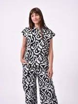 Remera blanca de manga corta con cuello redondo y un estampado abstracto en blanco y negro.