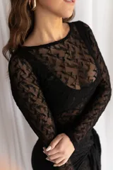 Vestido corto negro de encaje transparente, con mangas largas y falda ajustada con detalle lateral asimétrico tipo pareo.