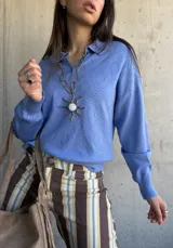 Sweater de punto celeste con cuello polo, cierre frontal parcial con botones y textura geométrica tipo rombos.