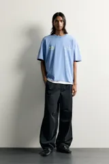 Camiseta relaxed fit de color celeste con efecto acid wash, cuello redondo y manga corta. Cuenta con estampa frontal con la inscripción "HOTEL STAFF" y "Escape Ibiza" en tonos amarillos.