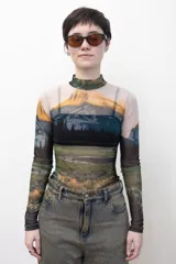Remera crop top de mangas largas y cuello alto, confeccionada en tejido de red transparente con estampado de paisaje montañoso.