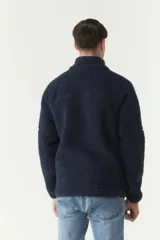 Campera de sherpa color verde militar, con cierre frontal completo, cuello alto y bolsillos laterales con cierre. Presenta un parche pequeño con logo en el pecho.