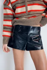 Shorts de tiro medio con efecto de cuero brillante en color negro, con cierre frontal y detalles de botones en la cintura.