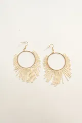 Par de aros colgantes con forma circular dorada y flecos de cuentas color crema.