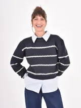 Buzo de tejido de punto en color azul marino con rayas horizontales blancas en diseño de zigzag. Presenta cuello redondo, mangas largas y puños acanalados.