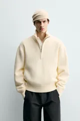 Jersey de punto color blanco con efecto pelo, cuello subido y cierre frontal de cremallera, de corte regular fit y manga larga con acabados en rib.