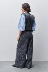 Pantalón de tiro alto con silueta amplia y piernas rectas, confeccionado en algodón con estampado floral. Cuenta con cierre frontal de botón y cremallera, y bolsillos laterales funcionales.