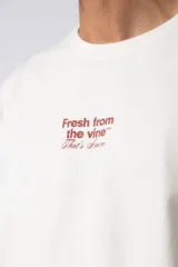 Remera de corte oversize color negro, con cuello redondo y mangas cortas. Presenta una estampa pequeña en el centro del pecho con la frase 'Fresh from the vine' en tipografía blanca.