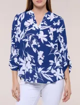 Blusa de gasa de calce suelto y caída ligera, color azul con estampado floral blanco. Presenta escote en V con cuello mao, tabla central, mangas largas regulables con presilla y botón, ruedo redondeado de estilo mullet y espalda con canesú y pliegue central.