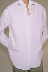 Camisa de manga larga confeccionada en hilatura con mezcla de algodón, con cuello solapa, bajo redondeado y cierre frontal oculto con botones.