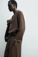 Camisa de manga larga color marrón oscuro, con cuello solapa y abertura frontal, confeccionada en tejido fluido con mezcla de modal. Presenta un calce relajado y aberturas laterales en el bajo.