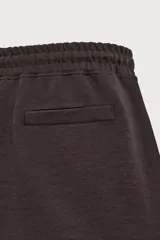 Bermuda estilo jogger de ajuste relajado, color negro, confeccionada en tejido interlock de algodón. Cuenta con cintura elástica ajustable mediante cordón, bolsillos delanteros tipo vivo y diseño liso.