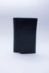 Billetera negra de cuero con textura tipo cocodrilo, con múltiples ranuras para tarjetas y billetes.