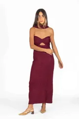 Vestido largo bordó con acabado brillante, diseño strapless con corte estructurado en el busto y abertura frontal tipo cutout, acompañado de un cuello halter integrado de tela a juego.