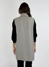 Chaleco largo color beige, con cuello solapa, un botón frontal y dos bolsillos de parche. Presenta costuras decorativas en contraste.