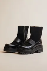 Botas negras de cuero con caña media, plataforma y hebilla decorativa.