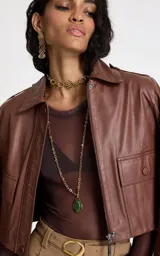 Collar largo de cadena de eslabones dorados con dije central ovalado de piedra verde engarzada en metal dorado.