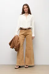 Jean de corte wide leg en color camel, con costuras verticales decorativas en el frente, tiro medio y cierre frontal con botón y cremallera.