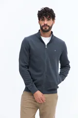 Campera de algodón color beige, estilo deportivo con cierre frontal, cuello alto y puños. Presenta bolsillos laterales y un pequeño logo bordado en el pecho.