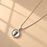 Collar de plata 925 con cadena de eslabones finos y dije circular con relieve de símbolo médico.