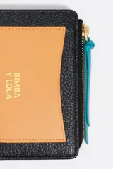 Billetera compacta de cuero vacuno en color negro, con cierre superior metálico dorado y logo de la marca estampado en el frente.