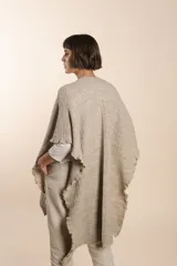 Ruana color crema tejida en punto fantasía con efecto de volado en los bordes.