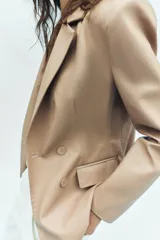 Blazer cruzado de efecto piel color bordó, con solapas de muesca, mangas largas y bolsillos con solapa en la parte delantera. Cierre frontal con botones a tono.